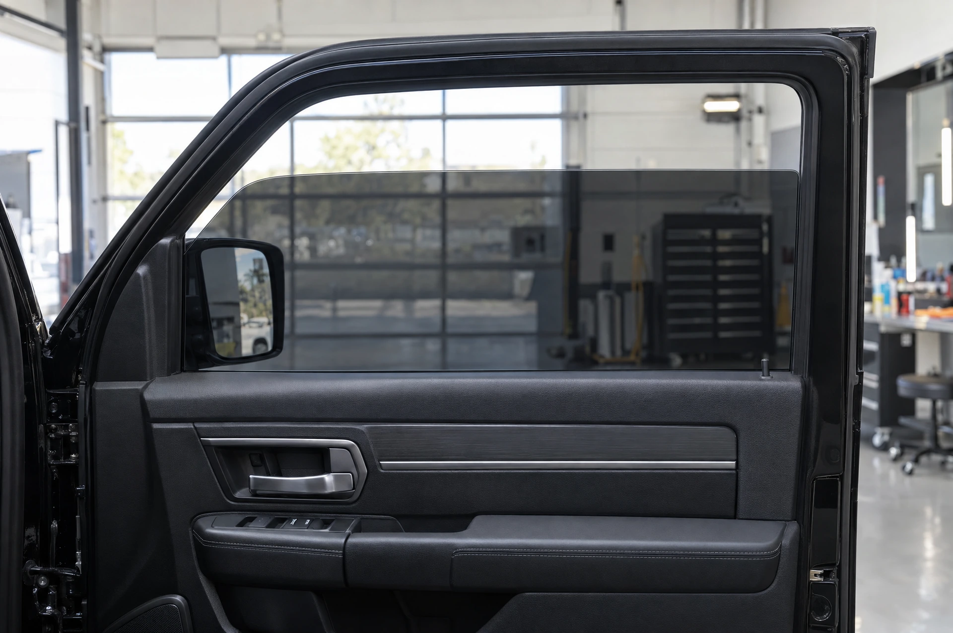 Finished charcoal tint on a partially lowered window in an open vehicle door