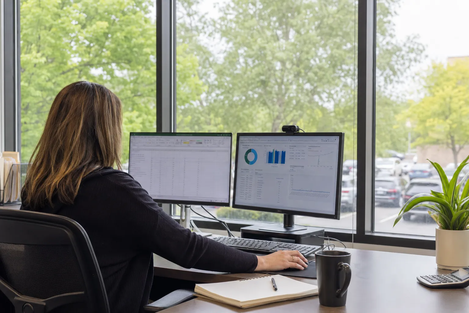 Office desk with glare-free computer screens beside a filmed window