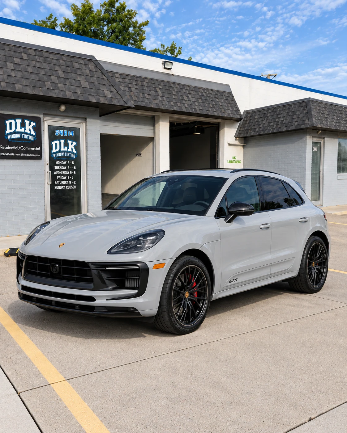 Illustration of a chalk light grey Porsche Macan GTS with tinted windows outside DLK's Mount Clemens shop