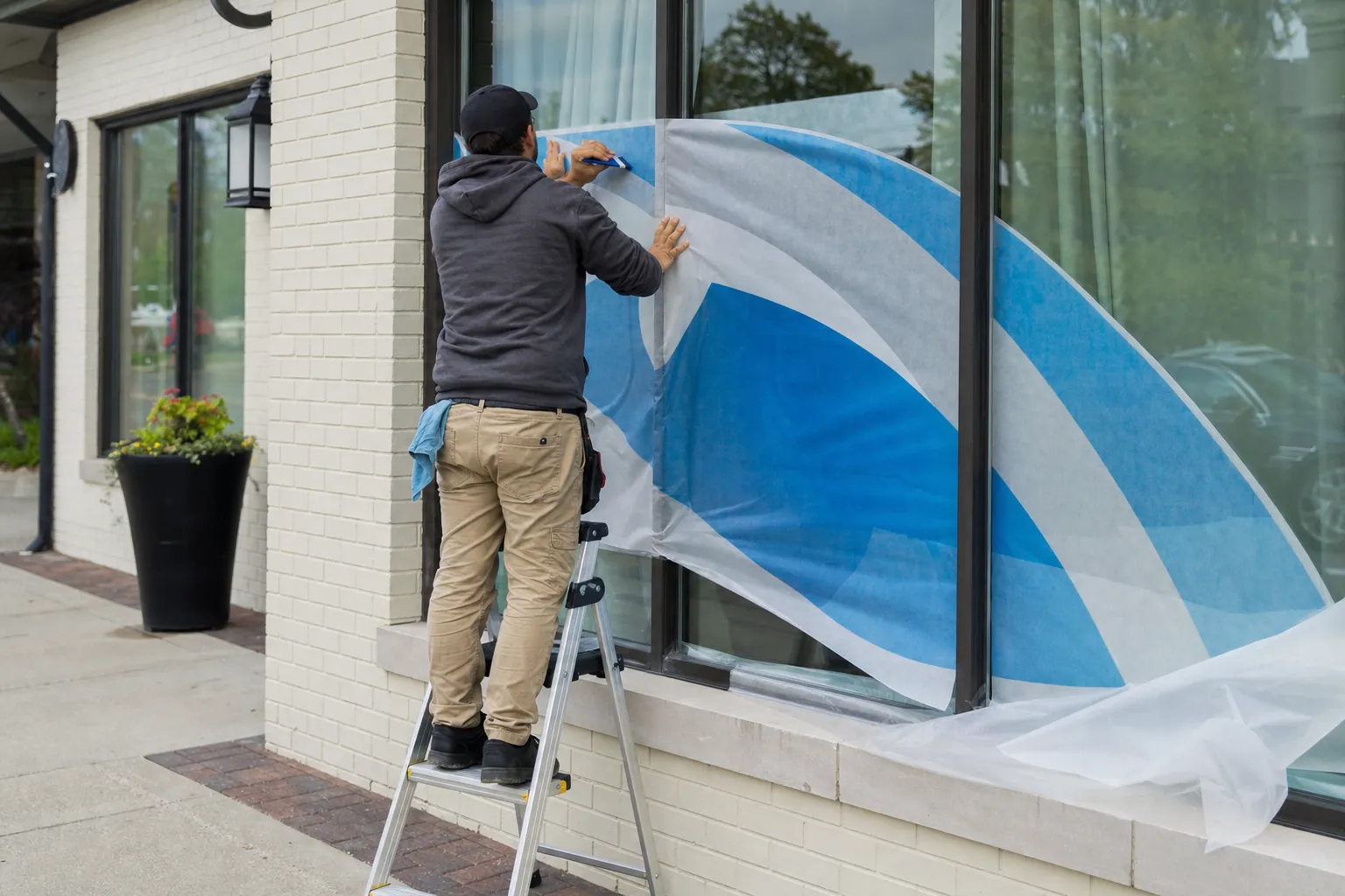 Installer applying large vinyl graphics to a shop window