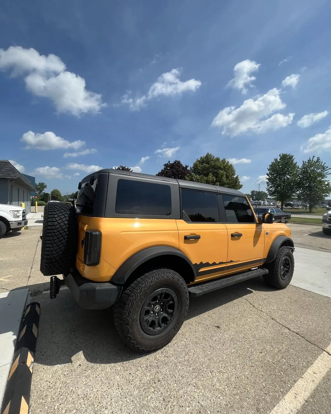 Orange Ford Bronco with tinted windows outside the DLK Window Tinting shop