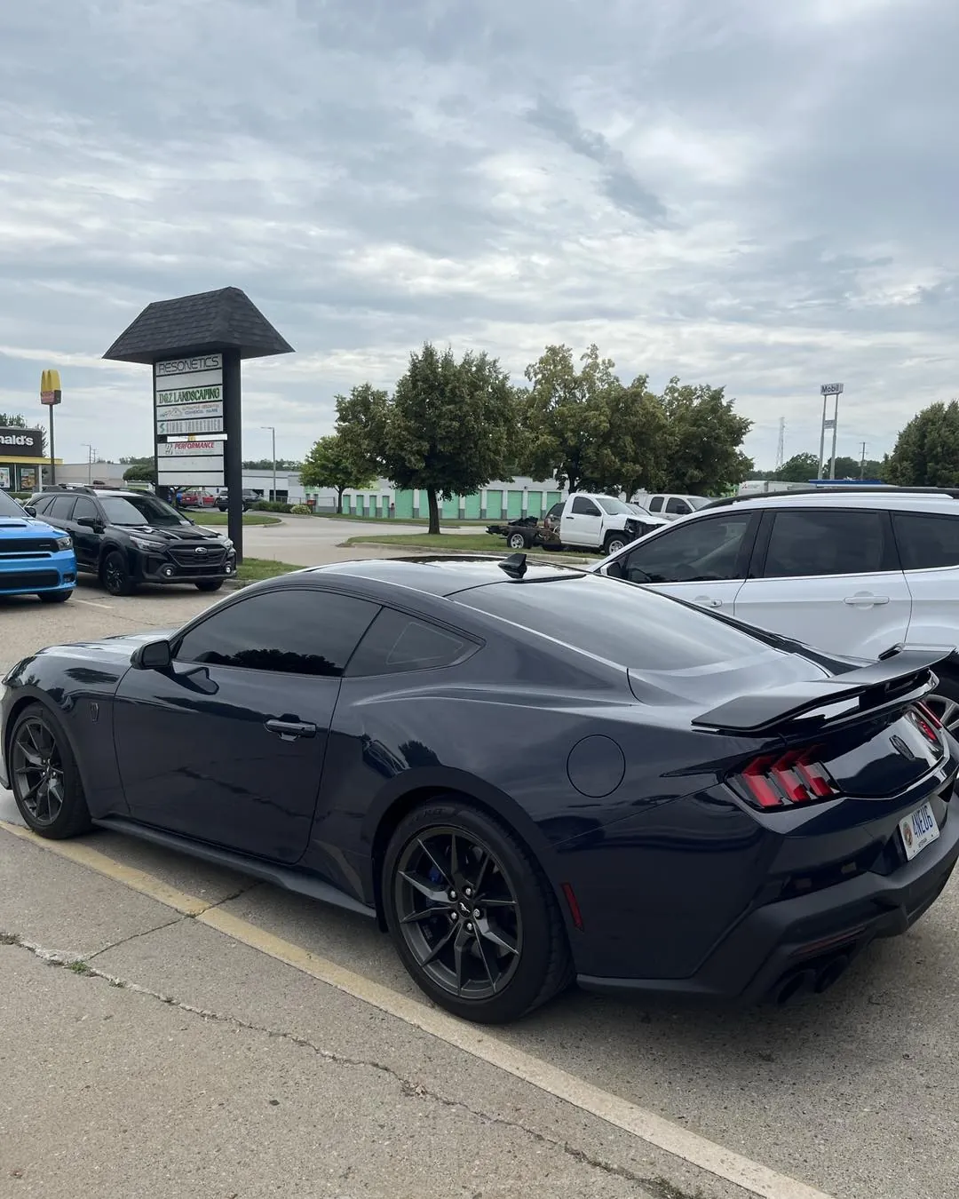 Dark Ford Mustang with tinted windows outside the DLK Window Tinting shop