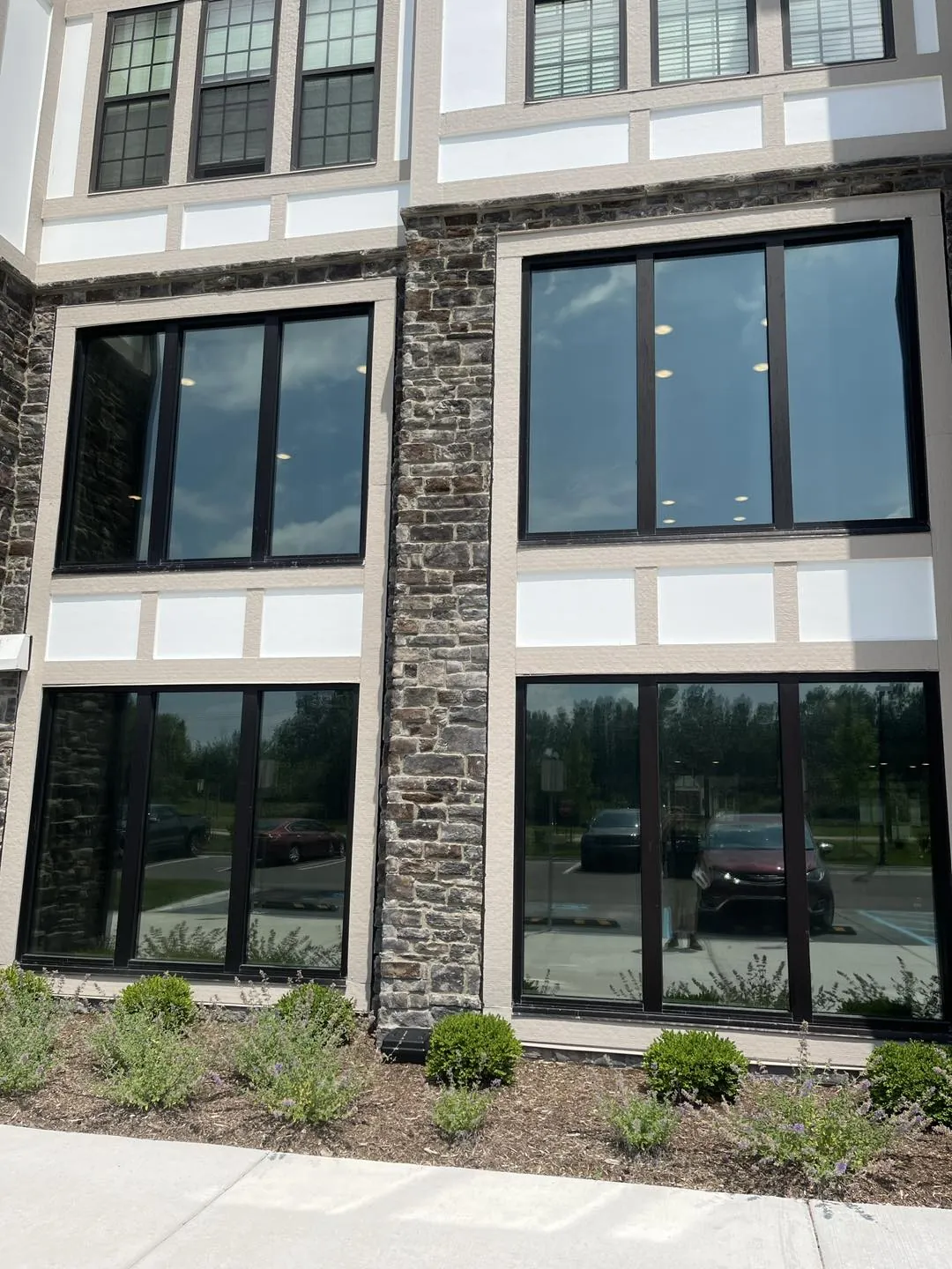 Stone-front building with black-framed windows fitted with window film